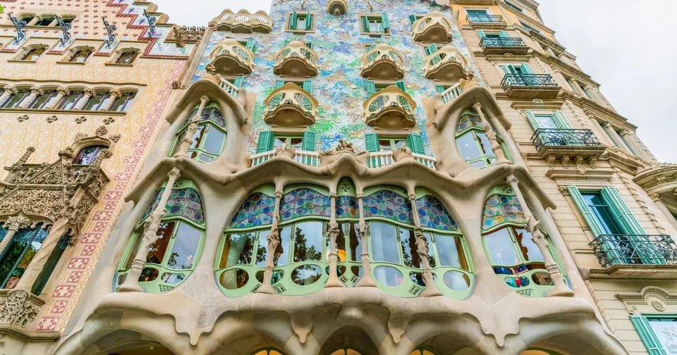 Eine Fassade, die mit blauem und grünem Mosaik bedeckt ist und knochenähnliche Fensterpfeiler hat