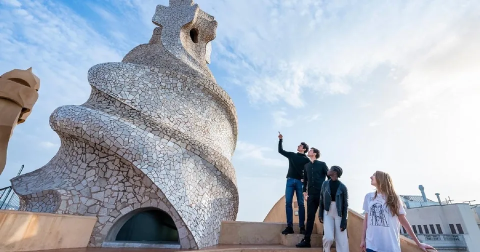 Ein spiralförmiger Dachturm, der mit weißem Mosaik verkleidet ist, mit Besuchern, die über die Stadt schauen